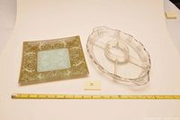 Both items displayed with measuring tape showing size, clear sectioned glass dish and square decorative plate with angel design.
