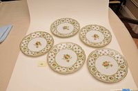 Set of six floral china luncheon plates with detailed floral bouquets and gold trim around edges.