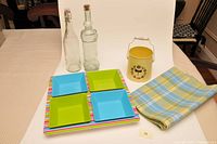 Photo showing all items together on a table: four-section tray with blue and green dishes, fabric runner, two glass bottles, and dragonfly container.