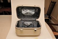 Open vintage cream-colored make-up travel case showing interior fabric lining, small pouch, and attached mirror.