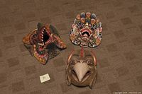Three vintage Balinese wooden masks arranged on carpet, showing details and colors