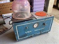 Front view of blue Vac-U-Cast unit with clear plastic dome and orange casting table pad