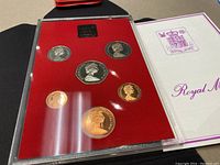 Full view of six coin set displayed on red backing with clear plastic cover and Royal Mint holder.