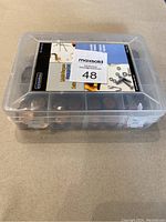 Closed plastic box with visible MaxSold label and compartments filled with coins.