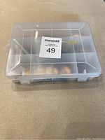 Plastic transparent box with secure latch, showing multiple compartments containing a variety of coins inside.