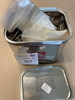 Top view of open Illy branded metal tin filled with plastic bags containing coins and rolls