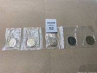 Five 1968 Canadian one dollar coins sealed in plastic sleeves, laid out in a row for display.