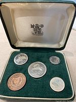 Top view of five Cyprus proof coins displayed in a green velvet lined case with satin lid showing official crest.