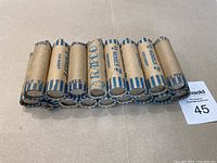 Seventeen paper rolls of Canadian five cent coins, folded neatly side by side.