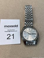 Front view of Seiko automatic watch showing silver dial, day-date window, and stainless steel bracelet.