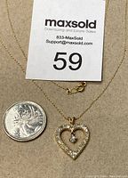 Pendant and chain laid flat with comparator coin and lot number card