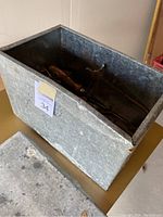 Metal box containing assorted jeweller's tools with visible screw clamp and wooden handles