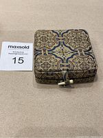Square decorative presentation case with intricate pattern, clasp closure.