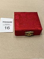 Closed red fabric box with gold-tone clasp holding the medal inside.