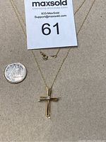 Front view of cross pendant and chain with coin for scale