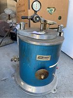 Front view of blue cylindrical injector with gauge and regulator on lid