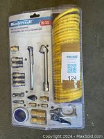 Full view of the Mastercraft air tool accessory kit, showing the 20 metal accessory pieces and the yellow coiled air hose all sealed in packaging.