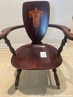 Front view of antique wooden armchair showing carved armrests, turned legs, and shield backrest with inlay.