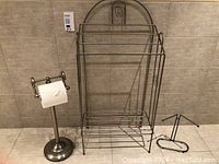 Photo of the three bathroom accessories: towel rack, toilet paper holder, and small towel holder together.