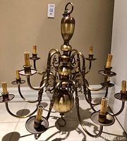 Side view of brass chandelier showing upper and lower tiers with candle-style sockets.