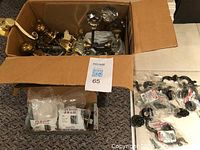 Box with assorted vintage crystal and brass door knobs, solid brass pocket door handles, and cabinet handles, showing condition and variety.