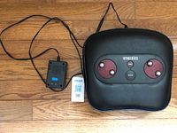Top-down photo showing the black Homedics foot massager with power adapter and cord laid out on wooden floor.
