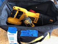 Top view of DeWalt cordless reciprocating saw inside a soft carrying bag with a blue label listing included items.