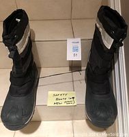 Front-facing image of the safety boots labeled size 9, showing black boots with reflective elements and rubber toe cap.