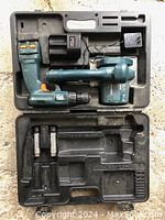 Open carrying case showing cordless drill, 4 inch saw attachment, battery charger, and batteries.