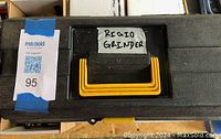 Closed black plastic carrying case with 'Rigid Grinder' label taped to lid, showing condition and tool storage container.