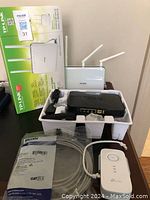 Overall view of the three routers including a white TP-Link router with box and antennas and black router in foam packaging.