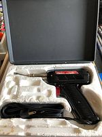 Open welding kit showing black handheld soldering tool with cord inside a styrofoam fitted case.