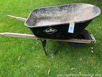 Side and angle view of the Garant wheelbarrow showing black metal tray, wooden handles, tire, and supporting frame