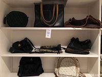 Shelving with nine purses and backpacks arranged in two rows.