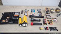 Full lot overview showing two yellow flashlights, two black flashlights, multiple battery packs, and a black plastic case with radio