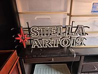 Photo of the full Stella Artois electric lighted sign resting on a table showing the front design and logo.