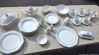 Full lot of collectible tableware laid on a table including plates, cups, bowls, serving dishes, and accessories.