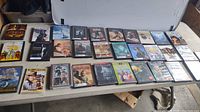 Photo showing 30 DVDs arranged on a table with visible titles including The Wizard of Oz, Sound of Music, Blade, Rawhide and others.