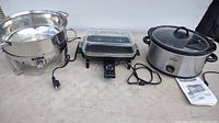 Wide photo of three electric cooking utensils on table: Bella chafing dish, WeeFry electric deep fryer, Rival slow cooker