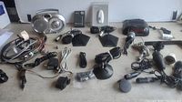 Lot of electronic items on table including multiple cables, power adapters, microphones, and audio accessories
