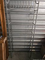 Metal bathroom stand full frontal view, showing open shelf design with three wire shelves and hooks on right side.