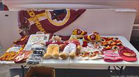 Table display showing multiple Washington Redskins memorabilia items including teddy bears, slippers, towels, caps, scarves, and collectibles