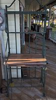 Front view of bakers rack with metal frame and wood shelves on porch floor.