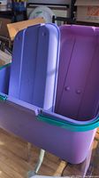 Purple plastic container with attached lid open showing the interior, green latch visible on the sides.