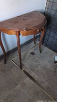 Wooden hall table with single drawer, curved legs and scalloped apron, surface wear visible