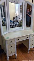 Front view of makeup table with triple mirror and palm tree theme in a bedroom.