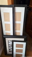Photo showing three black wooden picture frames with white mats. Two frames have multiple vertical photo slots and one has a single photo slot.