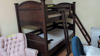 Photo of dark wood double bunk bed fully assembled with ladder leaning on side and two single mattresses on top and bottom bunks.