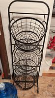 Front view showing three round wire baskets stacked vertically on metal frame.