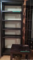 Dark wood bookcase with five shelves and matching coffee table with worn top surface beside it.